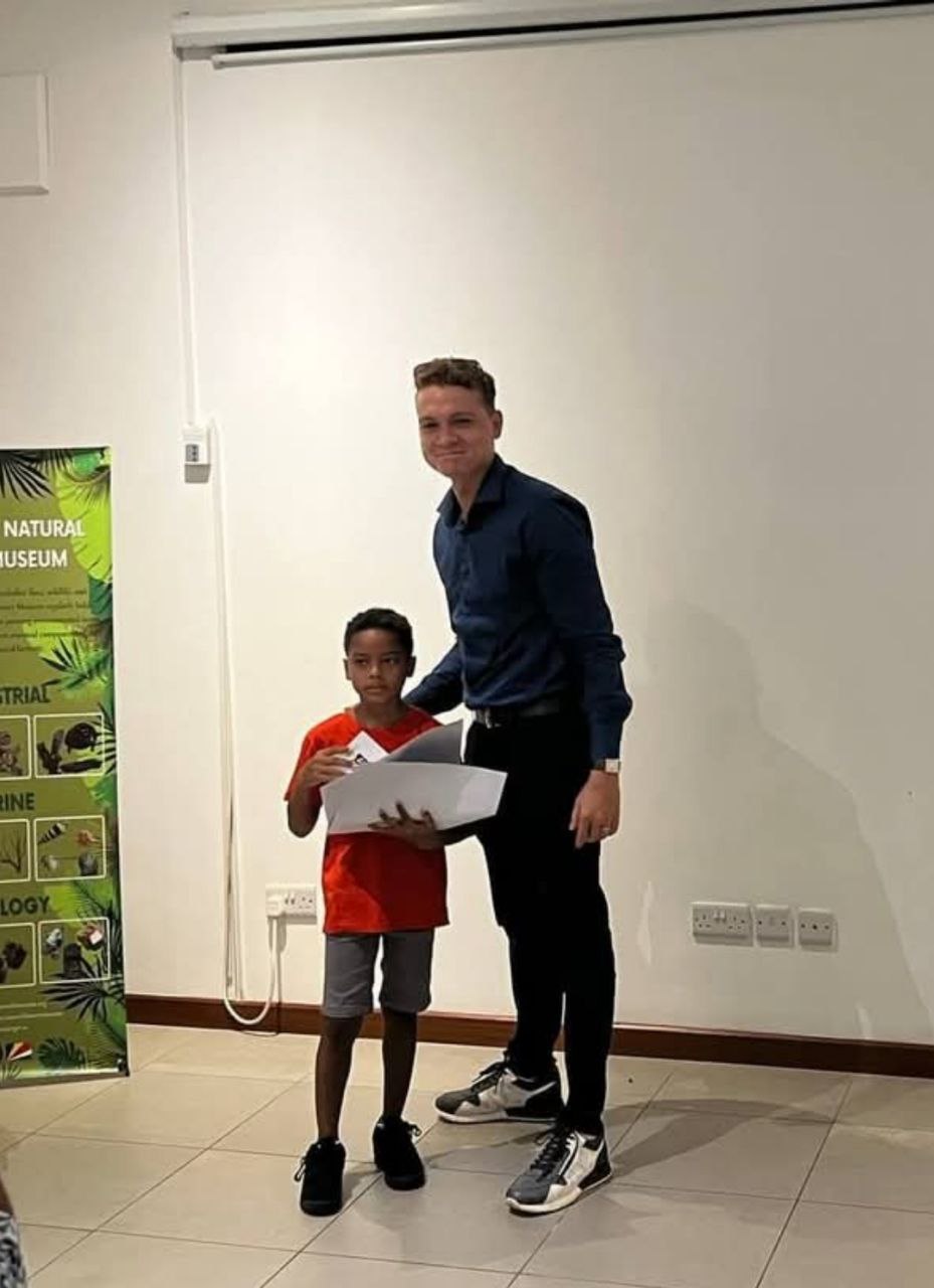 Salim Mathieu presenting an award to a young student at the Natural History Museum